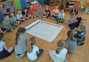 Dzieci oglądają przygotowaną grę planszową na macie do kodowania